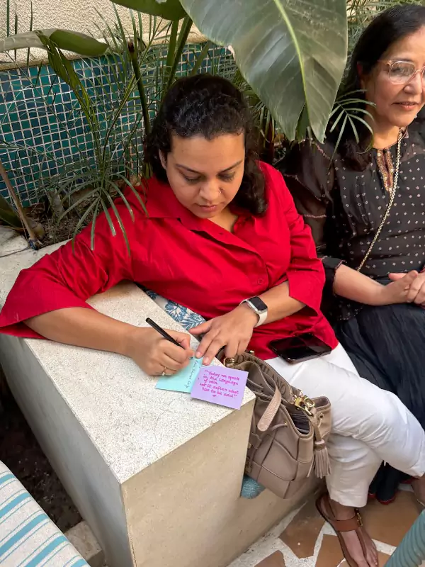 Participant writing verses on paper during Barish — In the Language of Rain poetry event